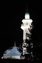 Illuminated white minaret of the mosque against the black night sky