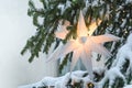 Illuminated white Moravian star (German Herrnhuter Stern) hanging in a snow covered Christmas fir tree Royalty Free Stock Photo