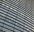 Illuminated windows on the facade of a large curved modern office building with lights turned on on at twilight