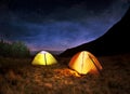 Illuminated yellow camping tent under stars