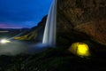 An illuminated yellow tent at beautiful Seljalandsfoss waterfall at night in Iceland Royalty Free Stock Photo