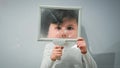 illusion and fun, cute male child playing with glass while distorting his face on white background