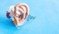 Illustration of an anatomical model of the human ear with luminous sound waves on blue background.