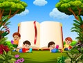 The children reading the book in the different posing with the big book in the garden Royalty Free Stock Photo