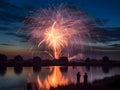 Illustration, colorful explosions of fireworks in the night sky over the lake, silhouettes of people watching. New Year\'s fu Royalty Free Stock Photo