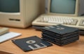 Illustration features retro tech. Stacked floppy disks sit on desk. Old computers and keyboards are visible in background. Royalty Free Stock Photo
