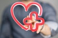 Illustration of a red heart with a medical cross and a man pointing at it - healthcare concept