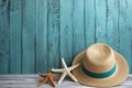 Illustration for summer vacation of a Hat, glasses, and starfish on a blue wooden background, in the style of serene seascapes.