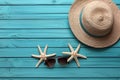 Illustration for summer vacation of a Hat, glasses, and starfish on a blue wooden background, in the style of serene seascapes.