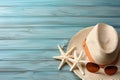 Illustration for summer vacation of a Hat, glasses, and starfish on a blue wooden background, in the style of serene seascapes.