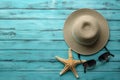 Illustration for summer vacation of a Hat, glasses, and starfish on a blue wooden background, in the style of serene seascapes.