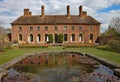 ILMINSTER, SOMERSET, ENGLAND - APRIL 15TH 2012: An English stately home sits behind an ornamental pond Royalty Free Stock Photo