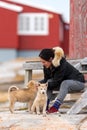 Young Inuit woman plays with a puppy of the Greenland sled dog husky