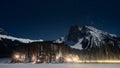 Iluminated alpine huts amongst the trees under the mountains and sky full of stars, winter, Canada Royalty Free Stock Photo