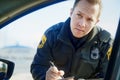 Im afraid Im gonna have to write you up. a handsome young male traffic officer issuing a ticket at a roadblock. Royalty Free Stock Photo