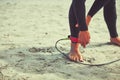 Im attached to surfing. a surfer tying his surfboard leash around his ankle.