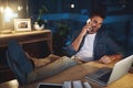 Im almost done, Ill be home soon. a handsome young businessman talking on his cellphone while sitting at his desk in a Royalty Free Stock Photo