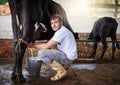 Im almost done milking this cow. Full length portrait of a young male farmhand milking a cow in the barn.