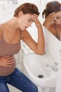 Im feeling so ill. A pregnant woman struggling with morning sickness in the bathroom.