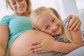 Im going to be the best big sister and babysitter. Portrait of a little girl hugging her mothers pregnant belly at home. Royalty Free Stock Photo
