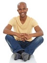 Im happy with who I am. A young ethnic man sitting crossed legged and smiling at the camera.