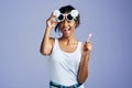 Im having a blast. Studio portrait of a beautiful young woman sucking on a lollipop against a purple background. Royalty Free Stock Photo