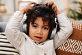 Im having a jam packed day. Portrait of an adorable little boy listening to music on headphones while sitting on a sofa Royalty Free Stock Photo