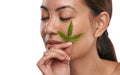 Im high on self-love. a beautiful young woman holding a marijuana leaf against her face.