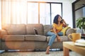 Im off today, wanna hang. Full length shot of an attractive young woman using her cellphone while relaxing at home on Royalty Free Stock Photo