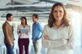 Im proud to be a part of this team. Portrait of a confident businesswoman posing in the office while her colleagues Royalty Free Stock Photo