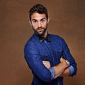 Im seriously into denim. a stylishly dressed young man posing against a brown background.