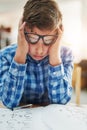 Im struggling with these. Portrait of a young boy looking stressed while being seated inside of a classroom during the Royalty Free Stock Photo