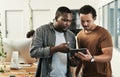 Im stuck with this one. two young businessmen standing together and using a digital tablet in the office. Royalty Free Stock Photo