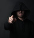 Im talking to you. Shot of an unidentifiable hooded man pointing while standing against a dark background. Royalty Free Stock Photo