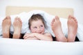 Im about to tickle them sshh..Fun shot of a young girl peeking out from between her parents feet while they lie in bed. Royalty Free Stock Photo