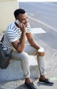 Im in town right now...A handsome casually dressed african american businessman sitting in the city and using his mobile Royalty Free Stock Photo