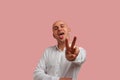 Im very fun guy. Carefree positive bald man with bristle makes peace gesture to camera and showing his tongue. Welcomes Royalty Free Stock Photo