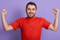 Imag eof excited happy young Caucasian man clenching his fists, celebrating his succses, posing isolated over purple background,