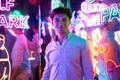 Image of an adult male in an amusement park in a room with neon light. Entertainment concept