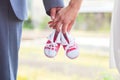 An image of adults holding baby pair of sneakers in red. Pregnancy and expectation.