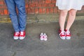An image of adults in red sneakers next to baby pair of sneakers. Pregnancy and expectation concept.