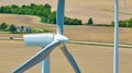 Aerial drone shot of wind turbines and blades with farmland below and house in distance