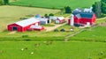 Aerial farmland with cows grazing in green pastures and red barn and red stable