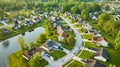 Aerial houses around pond in neighborhood suburban with distant housing construction in summer