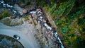 Aerial looking down at dirt road with white jeep near cliffs with river rapids below