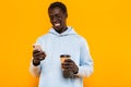 Image of african american guy holding cellphone and takeway coffee cup Royalty Free Stock Photo