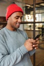 Image of african american man holding cellphone while working in office Royalty Free Stock Photo