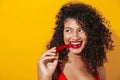 Image of african american woman wearing swimsuit eating chilly pepper Royalty Free Stock Photo