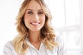 Image of alluring blonde woman smiling and standing in white office