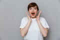 Image of amazed brunette woman wearing casual t-shirt screaming at camera